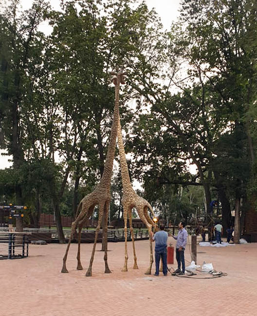 На этом фото скульптор с помощью паяльной лампы дорабатывает хвост жирафа